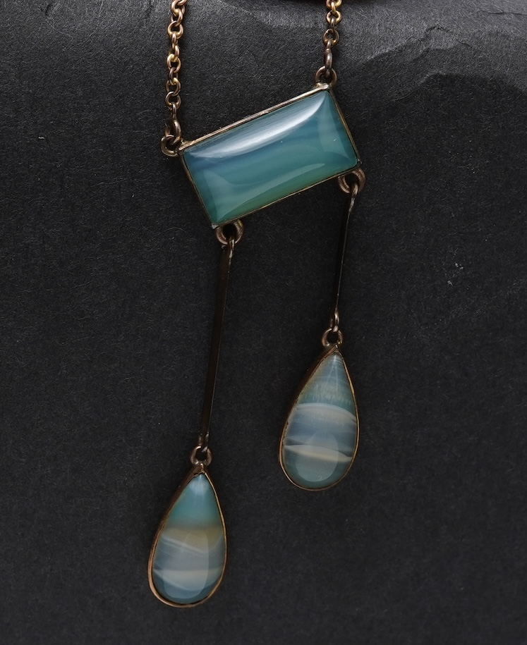 An Edwardian agate necklace, early 20th century, of negligée design, centring on a rectangular cabochon of translucent pale green agate, suspending a pair of pendants of unequal lengths, culminating in pear-shaped caboch